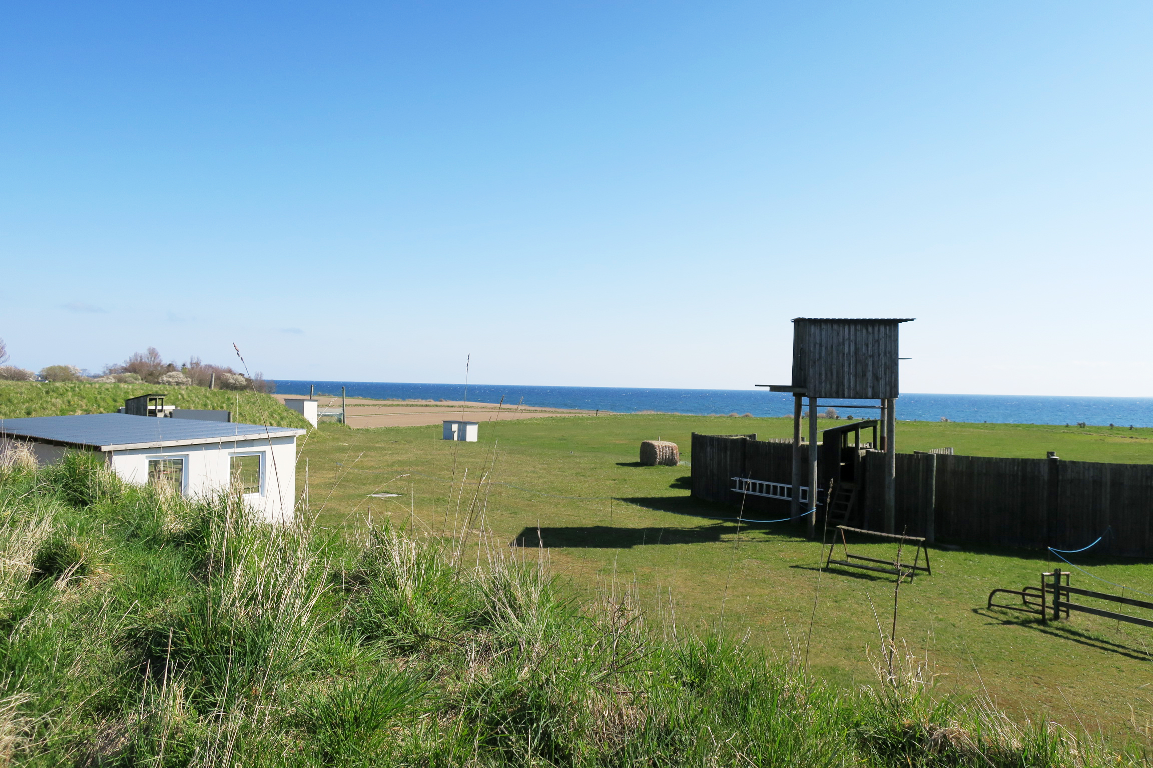 Overblik over skydebanen på Samsø. Hjælpere kan gratis overnatte med telte og campere på skydebanens område, tæt på skov og strand.